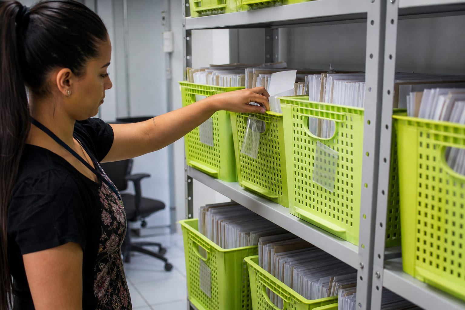 Armário de aço com pastas suspensas de documentos sendo aberto em um arquivo de recursos humanos